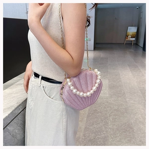Detail of pink pearlescent shell bag with pearl handle and golden chain strap