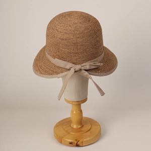 Detail of raffia sun hat featuring a delicate bow tie and intricate woven texture