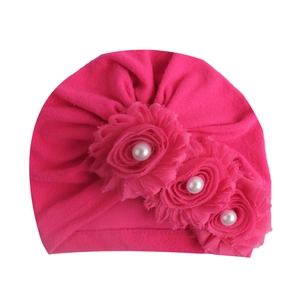 Detailansicht der rosaroten Babymütze mit Chiffonblumen und Perlenverzierung