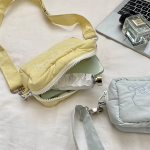 Detailed internal capacity showing small puffer crossbody bag with embroidery bow
