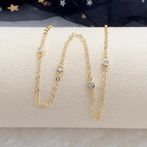 Close-up of golden choker necklace with sparkling round cubic zirconia on a beige display
