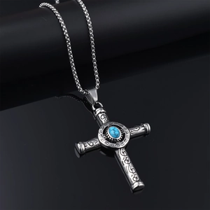 Detail of vintage silver cross pendant featuring a blue turquoise stone on black surface