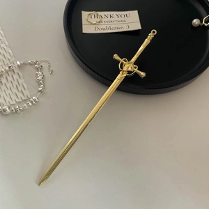 Detailed view of a golden sword-shaped hair pin with intricate tassels and pearls