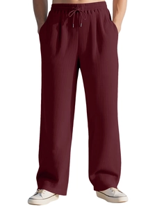 Detail of burgundy pleated fabric texture on men's relaxed wide leg trousers with drawstring