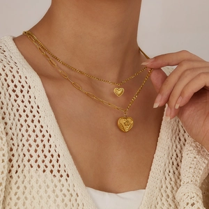 Close-up of double-layered gold heart necklace worn on a soft knit sweater background