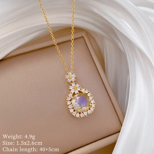 Close-up of a gold floral necklace with a yellow crystal pendant on a jewelry box