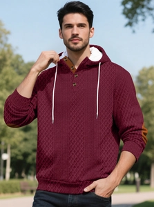 Détail d'un sweat à capuche bordeaux gaufré avec patte de boutonnage et patchs aux coudes