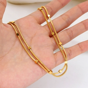 Detailed view of gold plated snake chain necklace with cubic beads held in palm