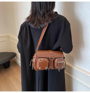 Brown leather underarm bag shown on model highlighting the vintage industrial biker style