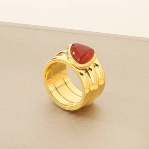 Detail of 18K gold plated knotted ring with a heart shaped red gemstone inlay