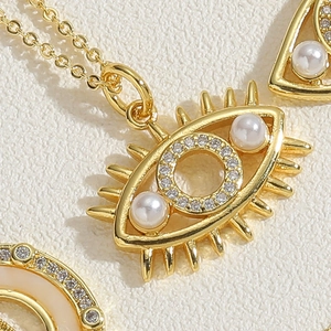 Macro shot of evil eye pendant featuring gold plating, micro-pave crystals and pearl details