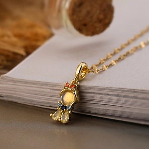 Macro shot of gold-plated astronaut pendant with colorful zircons on a book edge