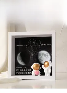 Detailed shadow box with personalized moon phase, star map, and cute astronaut figurines