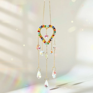 Macro shot of heart-shaped crystal suncatcher with golden wires and rainbow prisms
