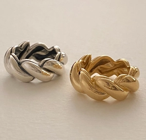 Detail shot of twisted silver and gold rings showing high-polished metallic texture