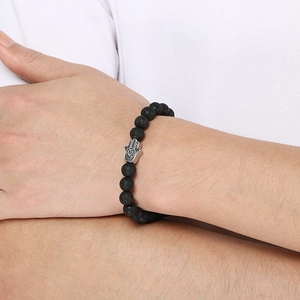Detailed close-up of a natural black lava rock bead bracelet with silver Hamsa hand charm
