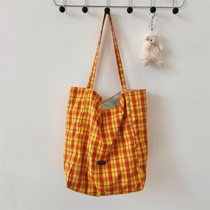 Detail of yellow plaid canvas tote bag with light green lining and plush sheep pendant