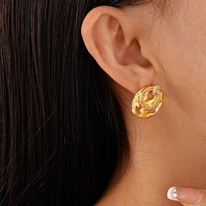 Close-up of golden irregular round zircon stud earrings worn on a female model