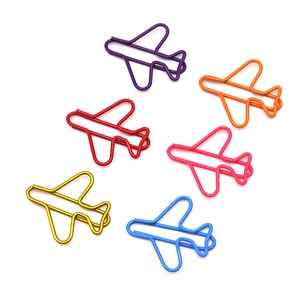 Top view of six colorful airplane-shaped metal paperclips scattered on a white background