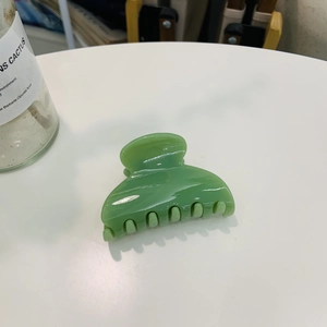Close-up of a glossy green heart-shaped plastic hair claw clip with smooth edges