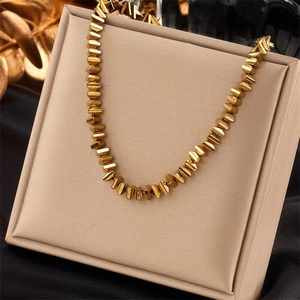 Golden geometric faceted bead necklace displayed on a luxury champagne velvet jewelry stand
