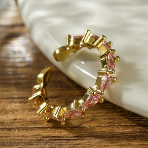 Detail of gold plated ring featuring marquise-cut pink zircon stones on white ceramic