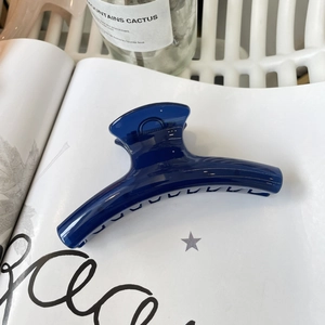 Detailed view of a glossy dark blue large hair claw clip on a stylish magazine