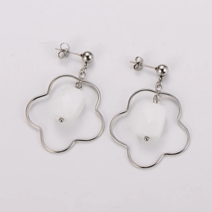 Detailed macro view of silver hollow flower earrings with faceted white pearl bead