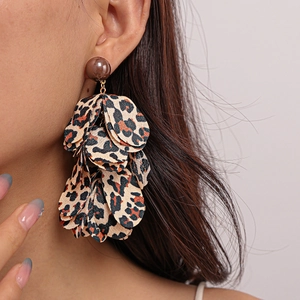 Close-up of leopard print chiffon petal earrings with fabric fringe on a female model