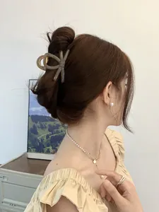 Detail of elegant coffee matte bow hair claw clip styled in a half-up ponytail