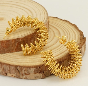 Close-up of 18K gold-plated irregular spiral hoop earrings on a natural wood surface