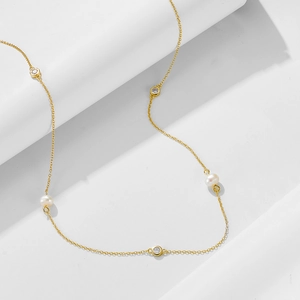 Detail of gold chain necklace with natural freshwater pearl and sparkling cubic zirconia