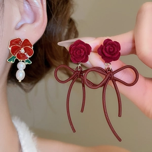 Detail view of red rose earrings with pearl charms and delicate ribbon accents
