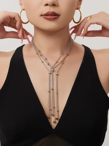 Détail d'un collier à pompons multicouche avec zircone et finition métal bicolore