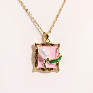 Detailed close-up of golden frame pendant with white tulip flower and natural pearl
