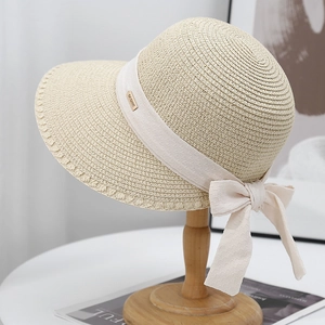 Detail of beige straw hat with cream ribbon, bow, and gold 'GO SWEET' metal tag