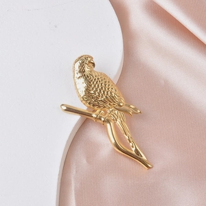 Close-up of golden metal parrot brooch on a branch with detailed feather texture