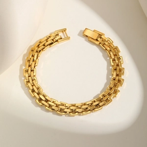 Modern 18K gold plated stainless steel watch-style link bracelet on beige surface