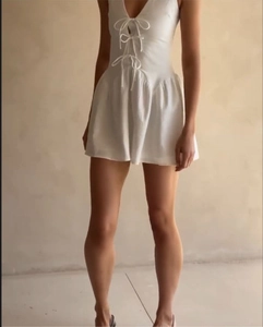 Detailed view of the front lace-up V-neckline and waist design on this white romper