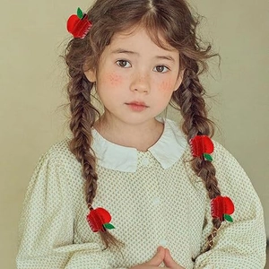 Close-up of red flocked apple-shaped hair claw clip on a model's braided hair