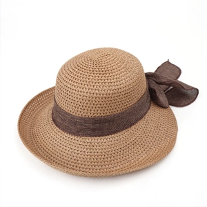 Detailed close-up of khaki woven straw hat with a large brown fabric bow and ribbon