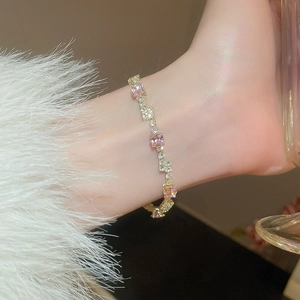 Close-up of gold bracelet featuring square pink and clear zircons on female wrist