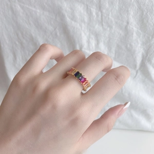 Hand model wearing a gold s925 silver ring with colorful rainbow rectangular zircons