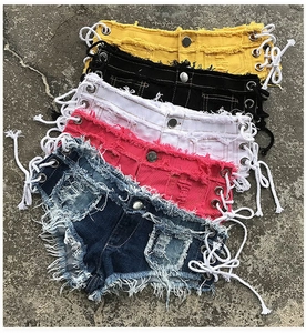 Dettaglio di pantaloncini di denim a vita bassa colorati con lacci laterali e frange