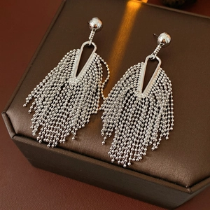 Detail of silver tassel earrings with triangle accents on a premium leather display