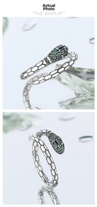 Macro detail of silver serpent ring featuring emerald green zircons and snake scale texture