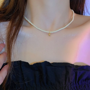 Collier élégant en perles blanches avec pendentif boule dorée sur un mannequin femme