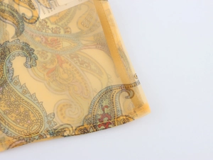Detailed macro shot of yellow paisley organza fabric with internal care label and stitching
