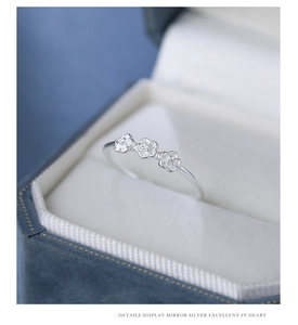 Macro shot of silver ring with three flower motifs and zircons in a blue velvet box