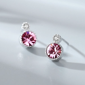 Macro detail of silver stud earrings featuring pink circular stones and tiny crystals